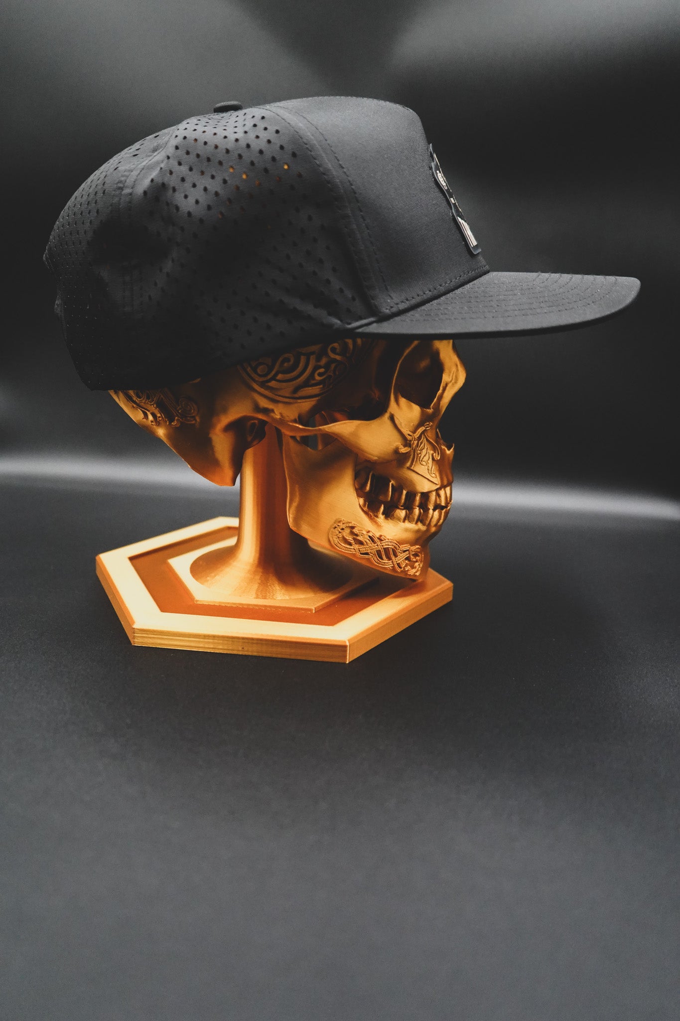 Gold skull sculpture with a black cap on a dark background